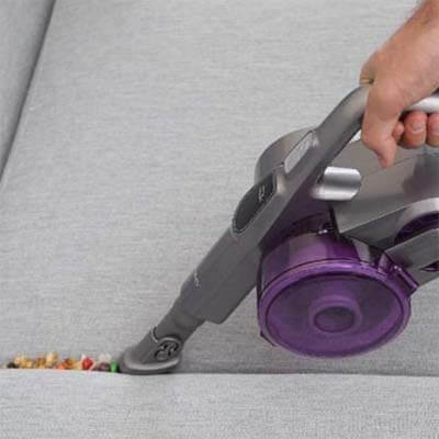 Vacuuming between the cushions of a sofa
